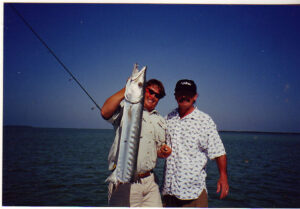 two guys holding a fish they just caught on the Time Flys boat.
