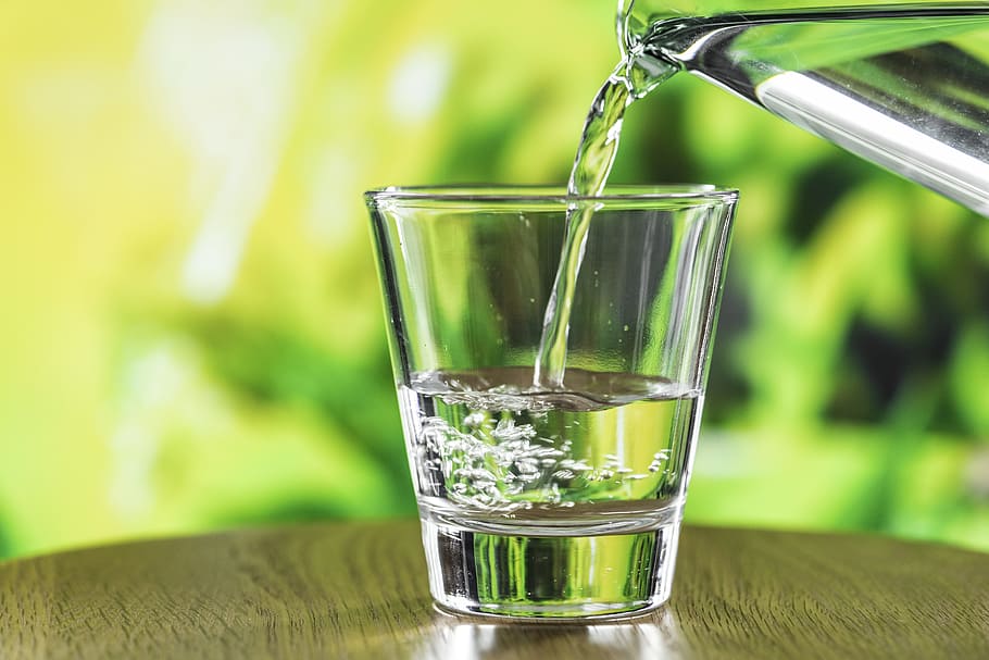 water being poured into a glass with a green background.